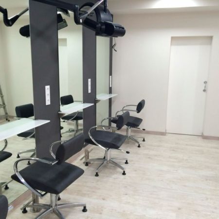 Imagen de varios sillones de peluquería con espejos a la izquierda y pared blanca al frente