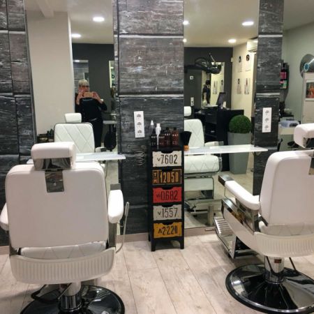 Detalle de dos sillones de peluquería blancos frente a espejos hasta el suelo